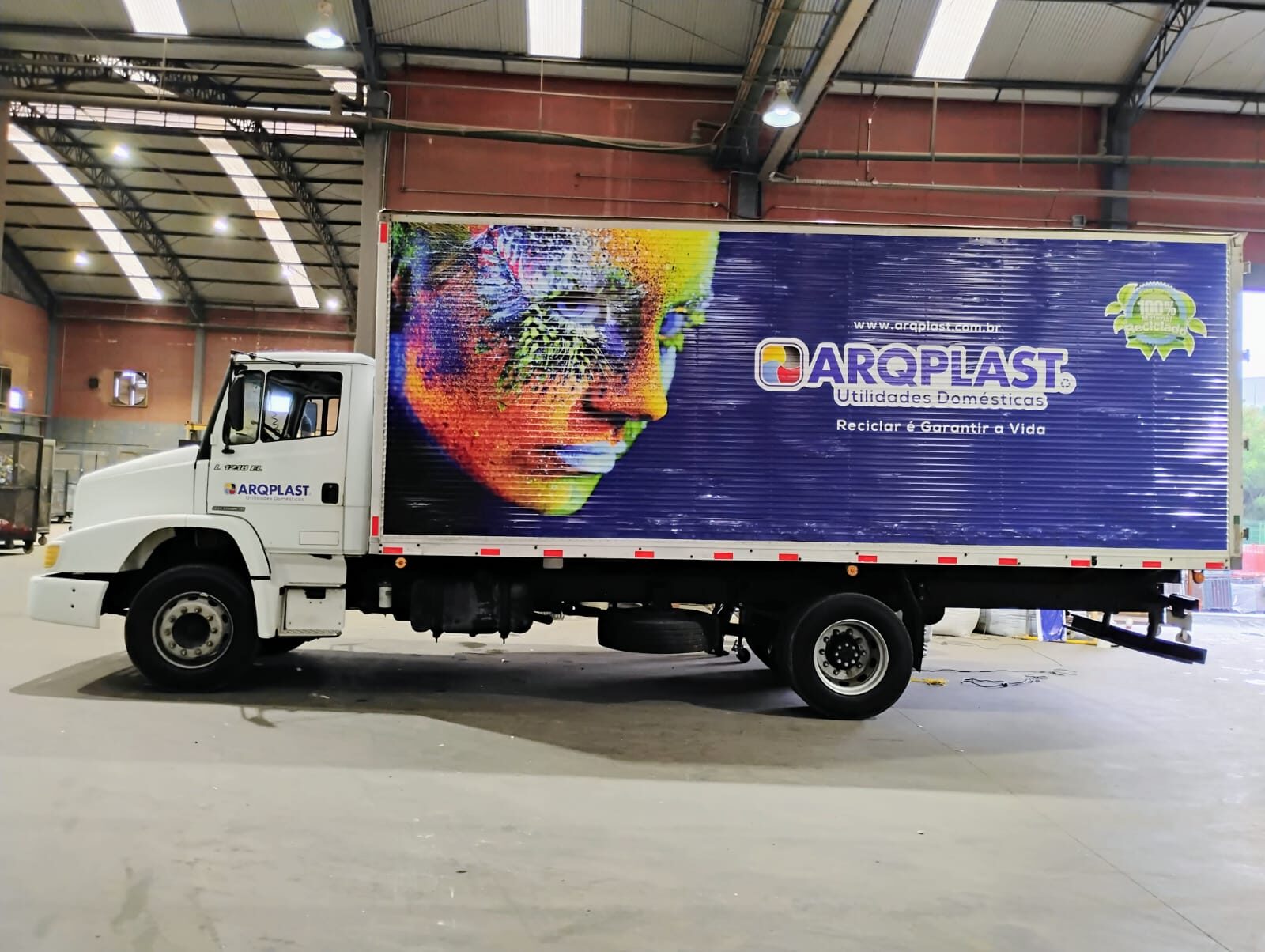 Caminhão baú envelopado em azul com a identidade visual completa da empresa Arqplast, executado pela DHB