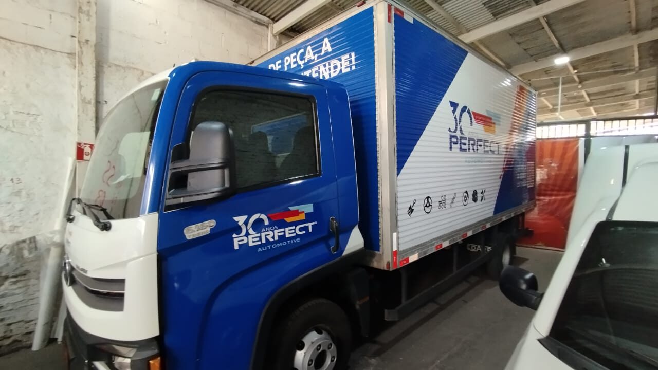 Caminhão de frota envelopado em azul e branco com a marca da empresa aplicada na cabine e no baú
